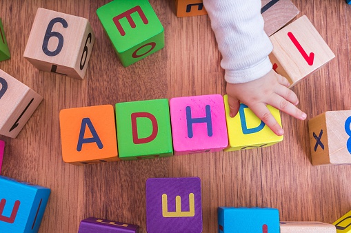 cuburile cu litere ale copiilor, aranjate pentru a forma numele ADHD, cu mâna copilului.