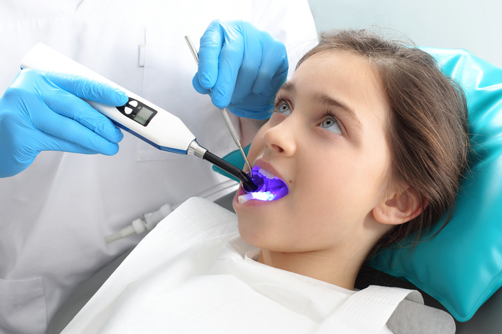 O fată în scaunul dentistului fiind tratată de dentist