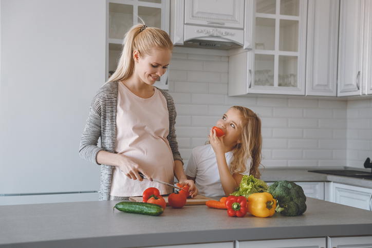 Mama și fiica însărcinată pregătesc o masă sănătoasă în bucătărie.