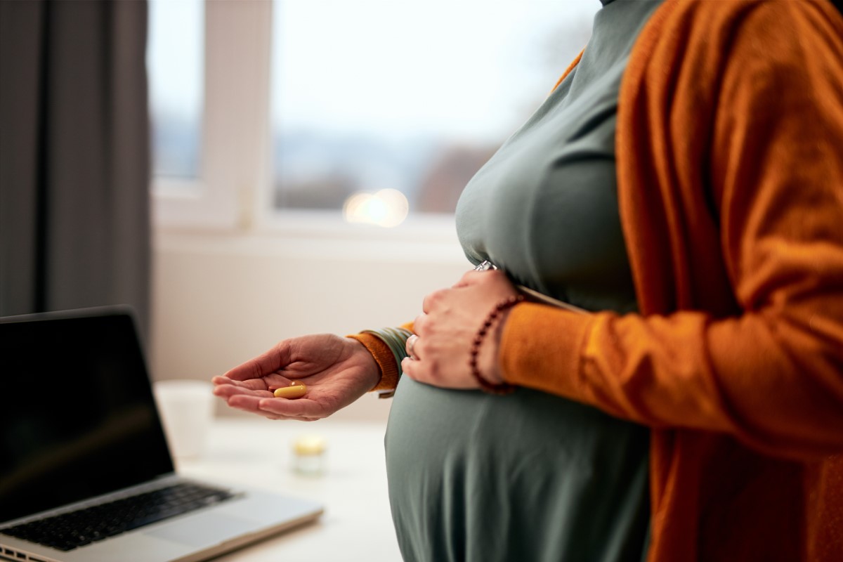 O femeie însărcinată ține în mână medicamente și nu știe care sunt cele mai potrivite din punct de vedere al siguranței.