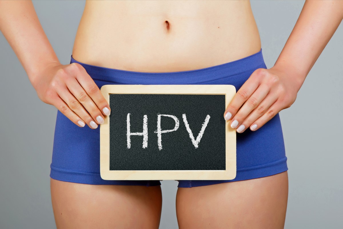 Femeie care ține un semn pe care scrie HPV